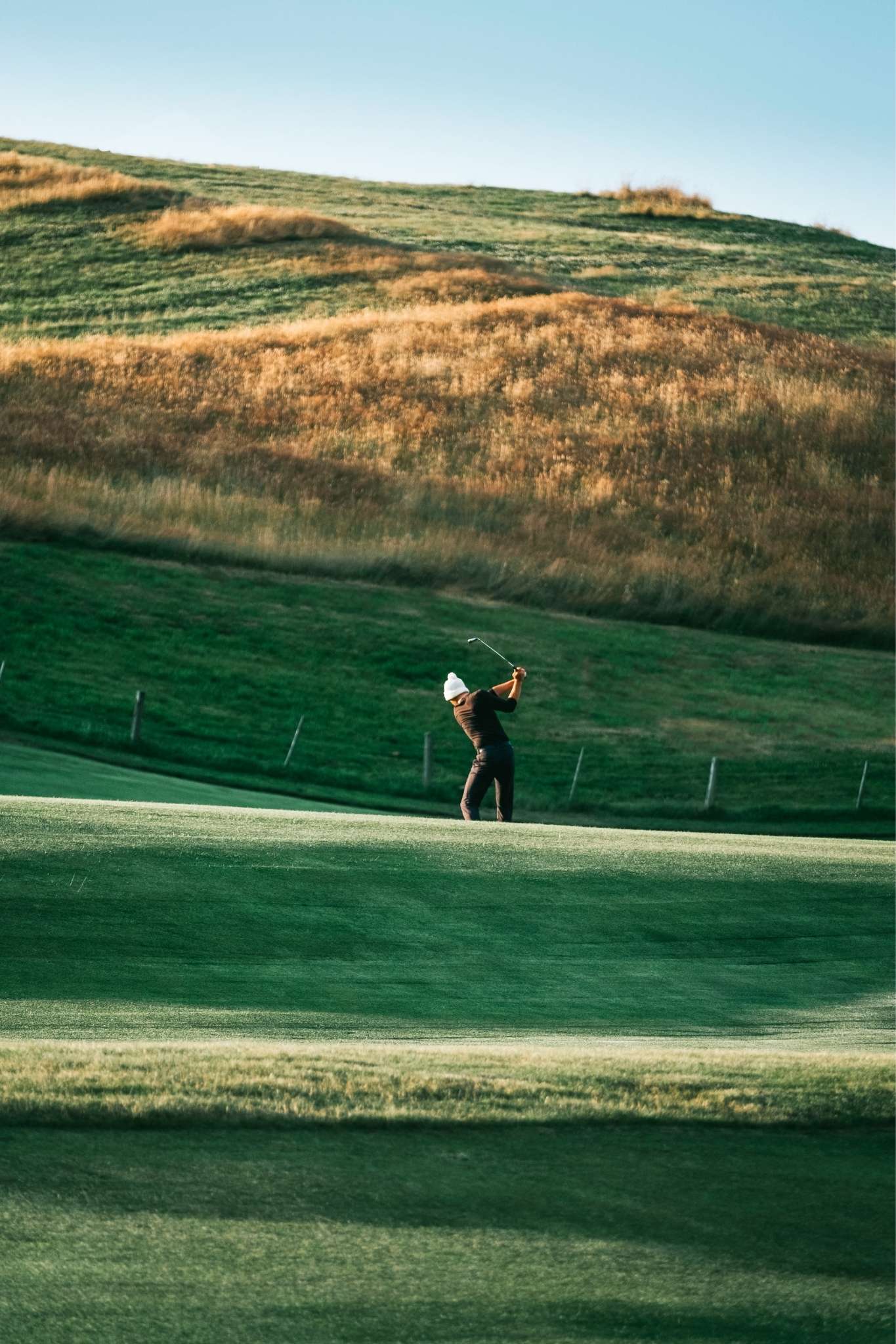 Wide angel of golfer chipping a ball on a golf course